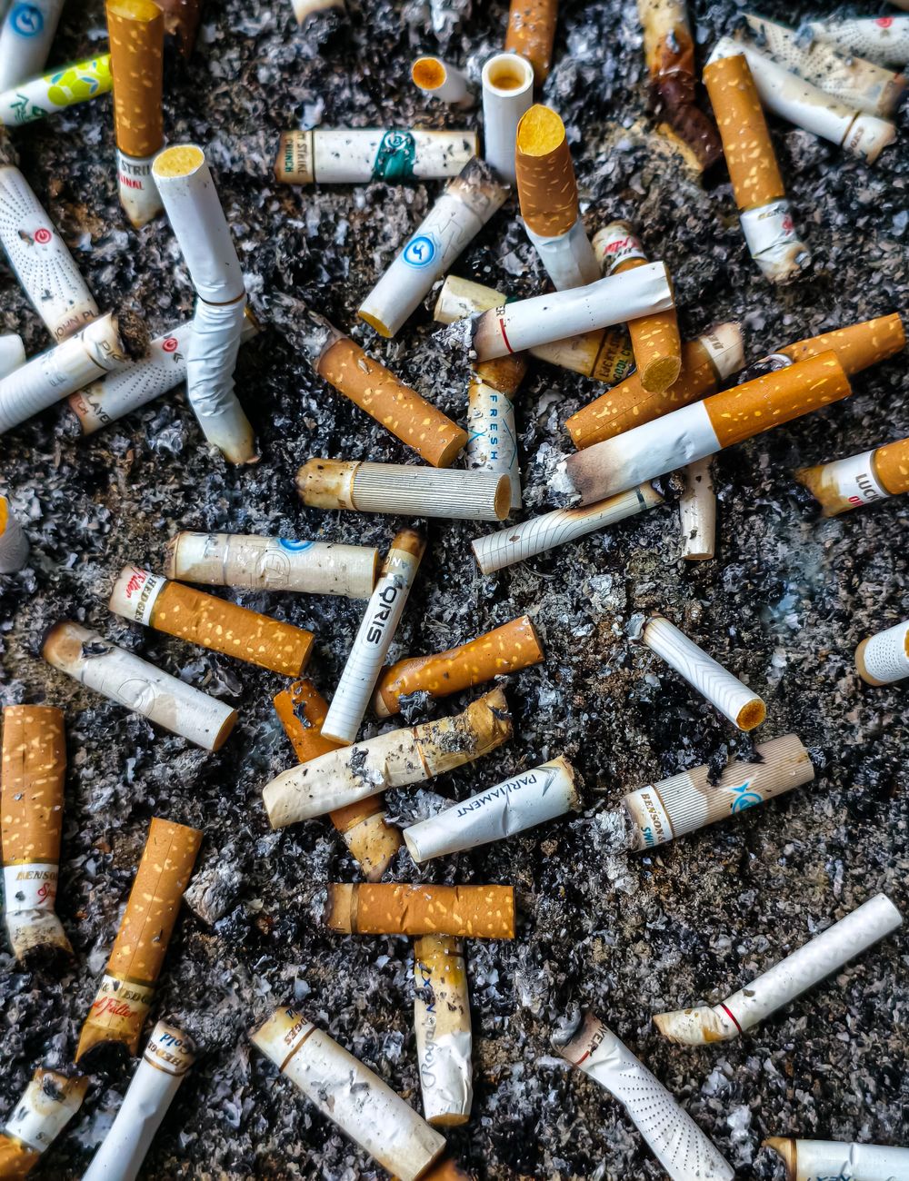 close up of multiple cigarette butts in ashtray